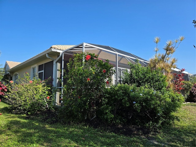 view of home's exterior with a lawn and glass enclosure