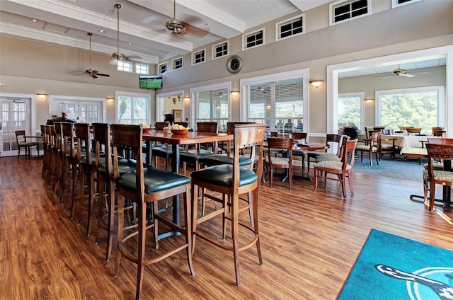 dining area with hardwood / wood-style flooring, ceiling fan, and beamed ceiling