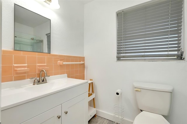 bathroom featuring vanity, tile walls, and toilet