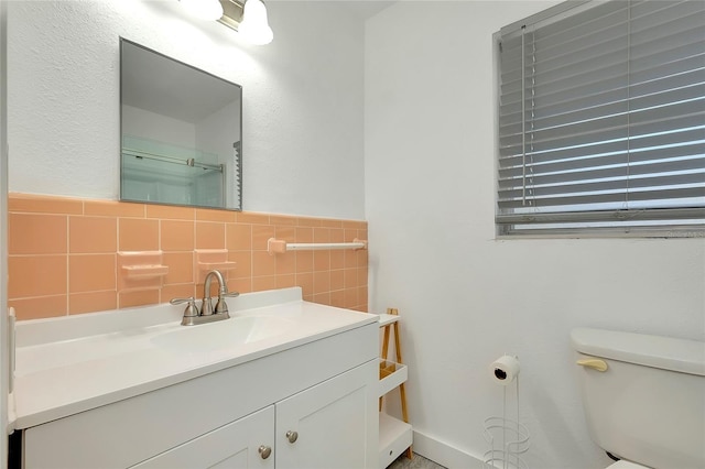 bathroom with vanity, toilet, and tile walls