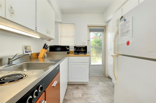 kitchen with white cabinetry, white fridge, sink, and light hardwood / wood-style flooring