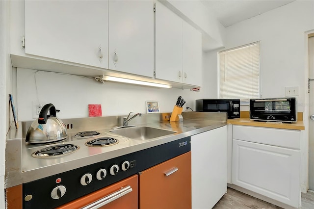 kitchen featuring stainless steel counters, sink, and white cabinets