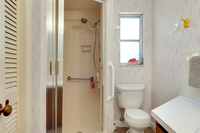 bathroom with tiled shower, vanity, and toilet