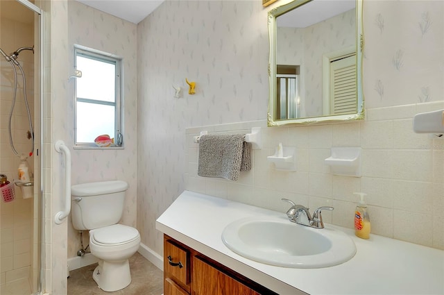 bathroom with vanity, a shower with door, tile walls, and toilet