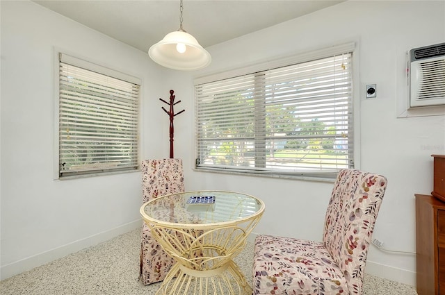 sitting room with a wall mounted AC and a wealth of natural light