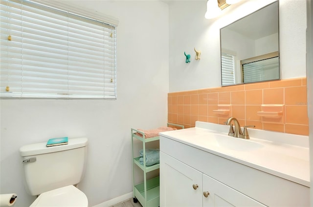 bathroom featuring vanity, toilet, and tile walls