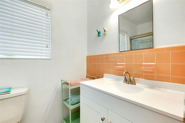 bathroom featuring vanity, toilet, and tile walls