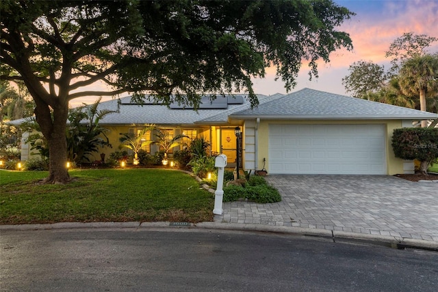 ranch-style house with a garage and a yard