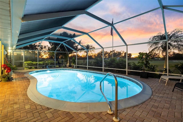 pool at dusk featuring a lanai and a patio area