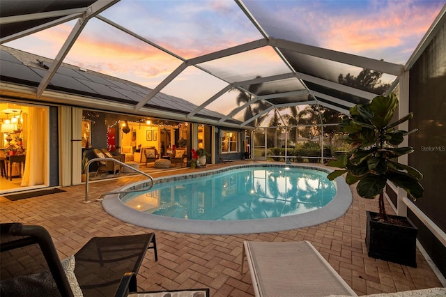 pool at dusk with a lanai and a patio area