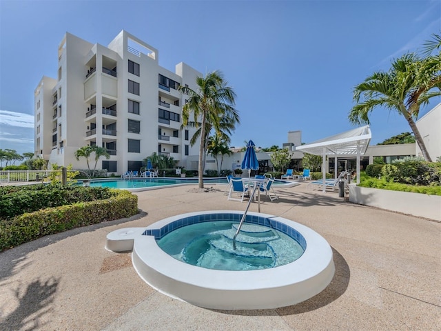 view of swimming pool with a hot tub and a patio area