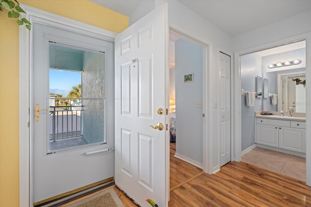 doorway to outside with light wood-type flooring and sink