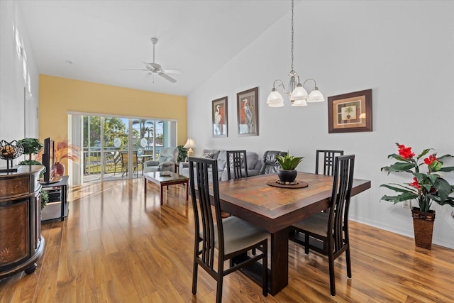 dining room featuring ceiling fan with notable chandelier, light hardwood / wood-style floors, and vaulted ceiling