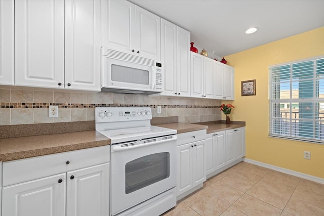 kitchen with light tile patterned floors, white appliances, white cabinetry, and backsplash