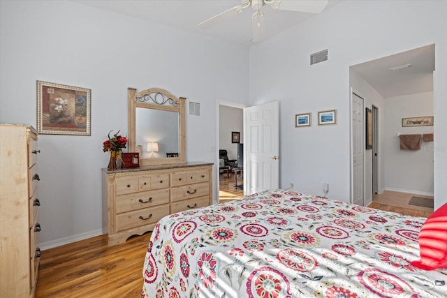 bedroom featuring a towering ceiling, light wood-type flooring, a closet, and ceiling fan