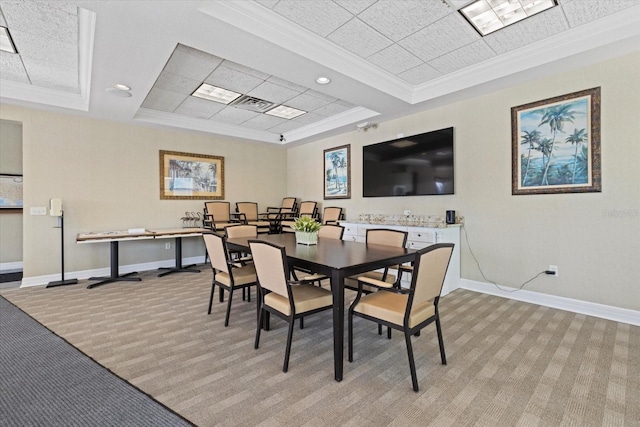 dining area with ornamental molding, a paneled ceiling, a tray ceiling, and light colored carpet