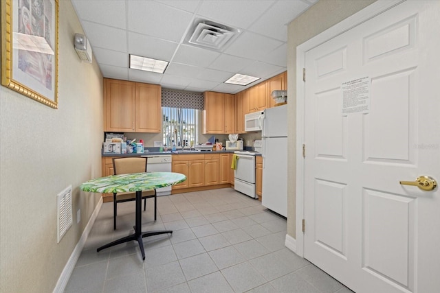 kitchen with a paneled ceiling, white appliances, and light tile patterned floors