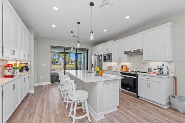 kitchen featuring appliances with stainless steel finishes, a center island with sink, and white cabinetry