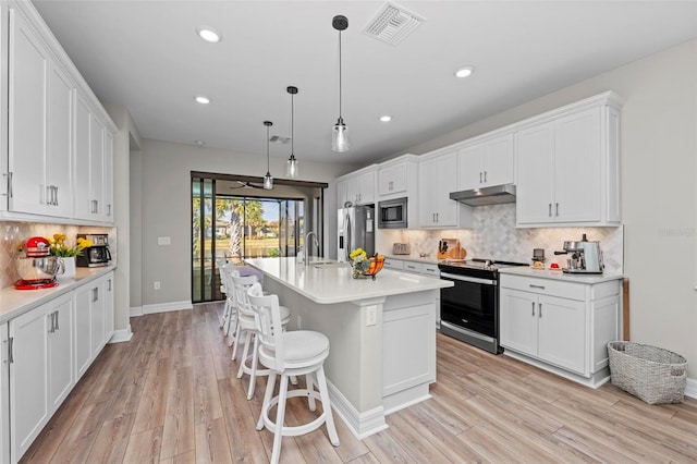 kitchen with a kitchen island with sink, white cabinets, sink, appliances with stainless steel finishes, and decorative light fixtures