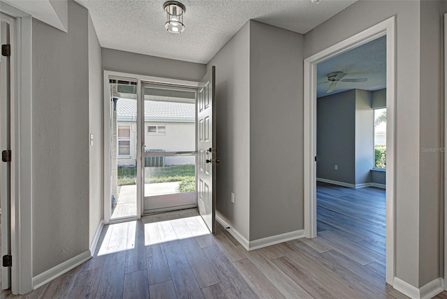 interior space featuring ceiling fan, a wealth of natural light, a textured ceiling, and light hardwood / wood-style flooring