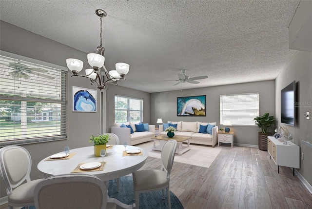 dining room with hardwood / wood-style flooring, ceiling fan with notable chandelier, and a textured ceiling