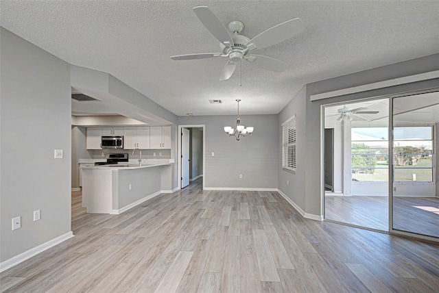 unfurnished living room featuring sink, ceiling fan with notable chandelier, light hardwood / wood-style floors, and a textured ceiling