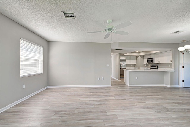 unfurnished living room featuring light hardwood / wood-style floors and ceiling fan with notable chandelier