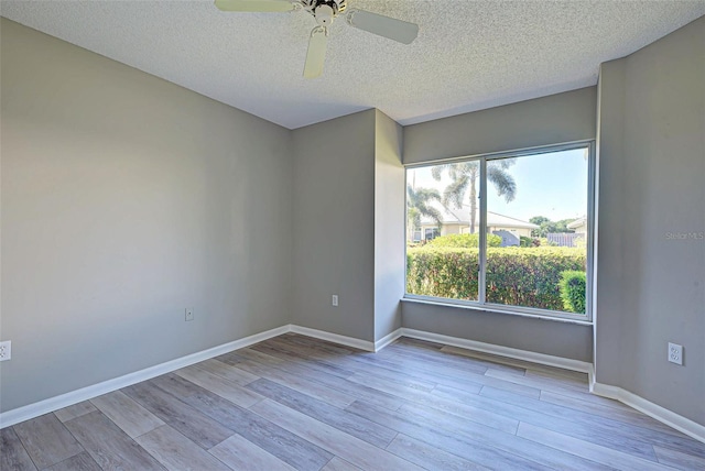 spare room featuring ceiling fan, a wealth of natural light, light hardwood / wood-style floors, and a textured ceiling