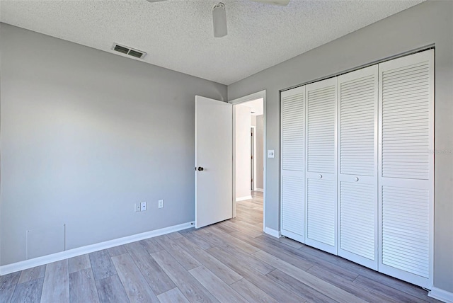 unfurnished bedroom featuring ceiling fan, light wood-type flooring, a closet, and a textured ceiling