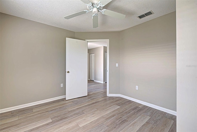 unfurnished room with ceiling fan, a textured ceiling, and light wood-type flooring