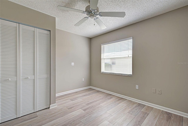 unfurnished bedroom with light hardwood / wood-style flooring, a textured ceiling, ceiling fan, and a closet