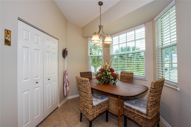 tiled dining area with vaulted ceiling and an inviting chandelier