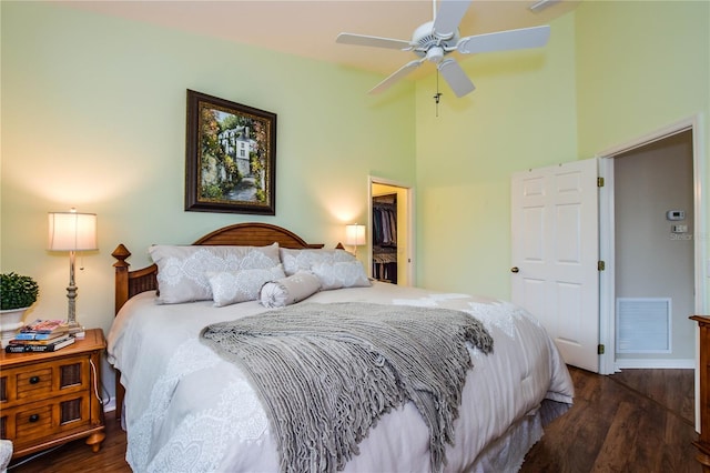 bedroom with ceiling fan, a closet, dark wood-type flooring, and a high ceiling