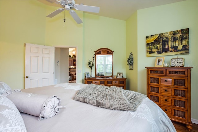 bedroom featuring a towering ceiling, hardwood / wood-style flooring, and ceiling fan