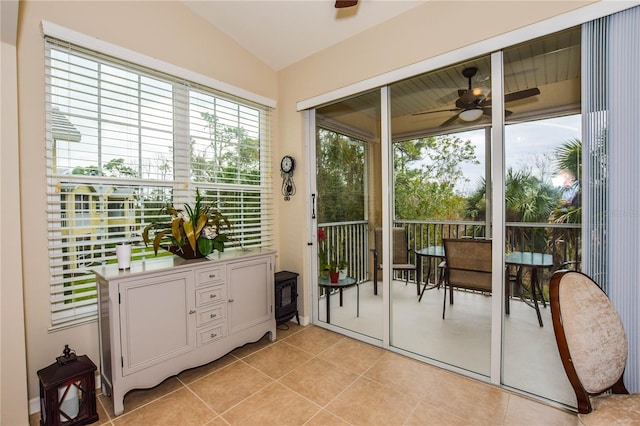 doorway featuring light tile patterned floors, ceiling fan, and lofted ceiling