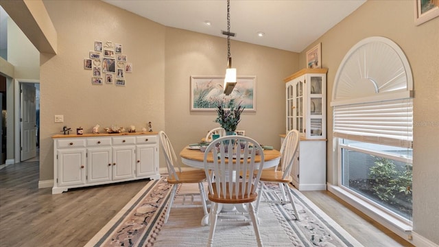 dining room featuring light wood-type flooring and vaulted ceiling