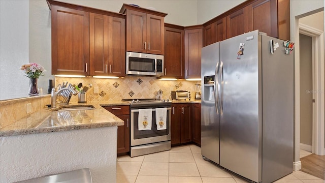 kitchen with stainless steel appliances, sink, light tile patterned floors, and kitchen peninsula