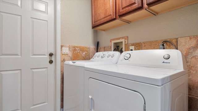 clothes washing area featuring cabinets and separate washer and dryer