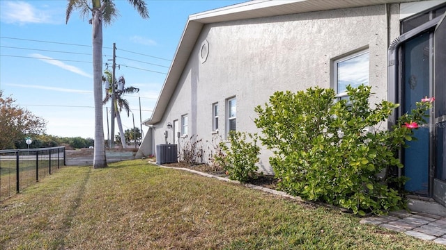 view of side of property featuring central air condition unit and a lawn