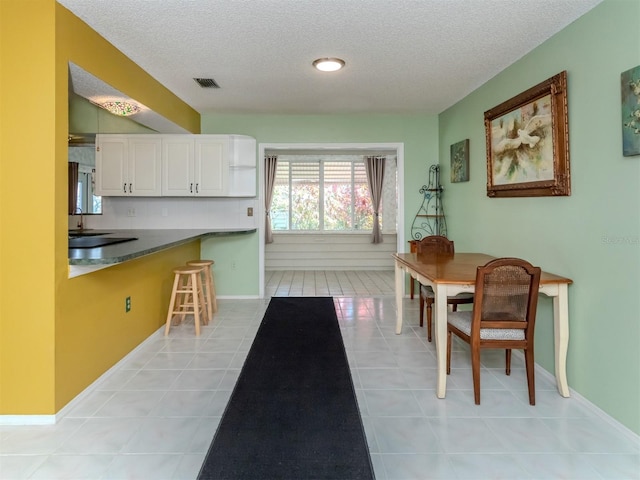 tiled dining space featuring a textured ceiling and sink