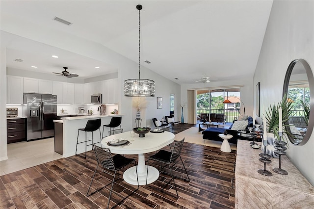 dining room featuring ceiling fan with notable chandelier and lofted ceiling