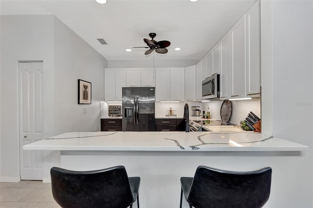 kitchen with stainless steel appliances, a breakfast bar area, white cabinets, and kitchen peninsula