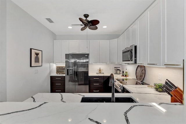 kitchen with light stone counters, stainless steel appliances, white cabinets, and dark brown cabinetry