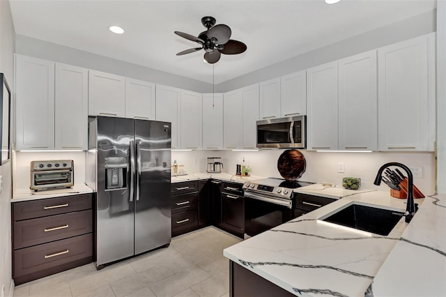 kitchen featuring light stone countertops, appliances with stainless steel finishes, white cabinetry, and sink