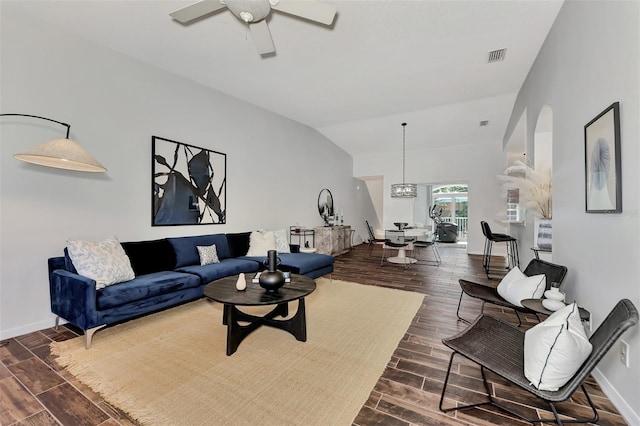 living room with ceiling fan with notable chandelier and vaulted ceiling