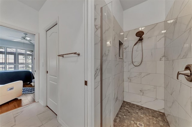 bathroom with a tile shower and ceiling fan