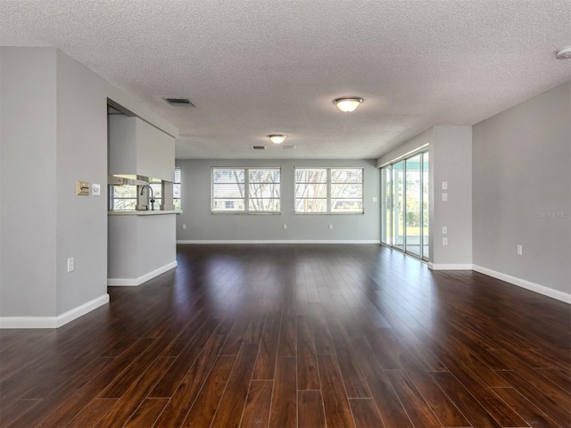 unfurnished room with dark wood-type flooring, a textured ceiling, and sink