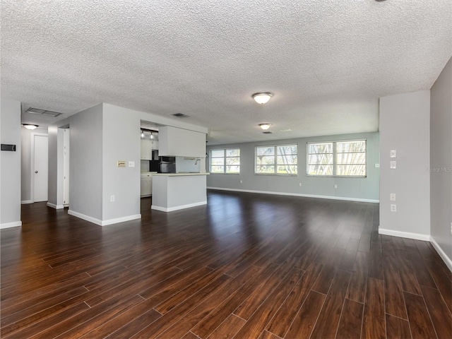 unfurnished living room featuring a textured ceiling and dark wood-type flooring