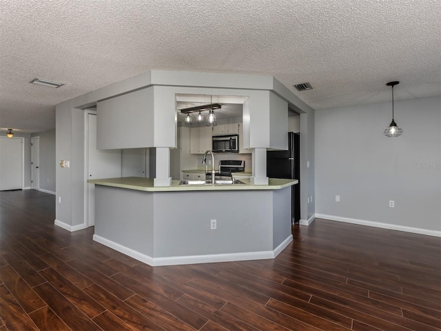 kitchen with a textured ceiling, white cabinets, stainless steel appliances, sink, and hanging light fixtures