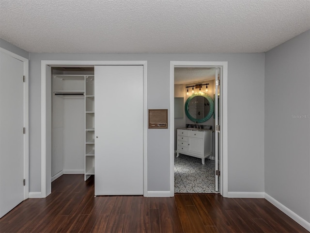 unfurnished bedroom with dark hardwood / wood-style floors, sink, connected bathroom, and a textured ceiling